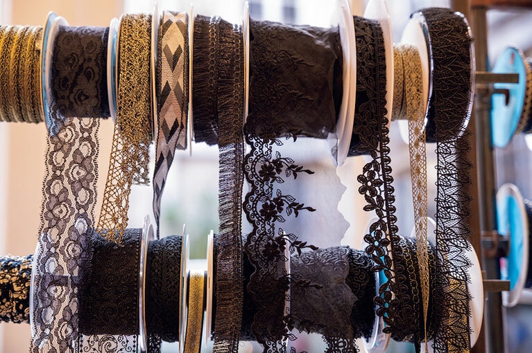 リザ氏の確かな目で選び抜かれたリボンが壁一面に並ぶ。職人が作るレースや絹のリボンは触れるだけで質の良さが伝わってくる。
