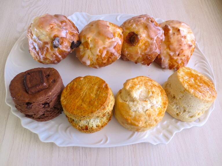 取材時のスコーン全種類。手前／左から「ダブルチョコ」352円、「アールグレイオレンジ」330円、「リッチバターソルト」330円、「プレーン」297円。奥はハワイアンスコーン／左から「ラムレーズン」385円、「マンゴー」385円、「バナナ」385円、「プレーン」352円。（テイクアウトは別価格）