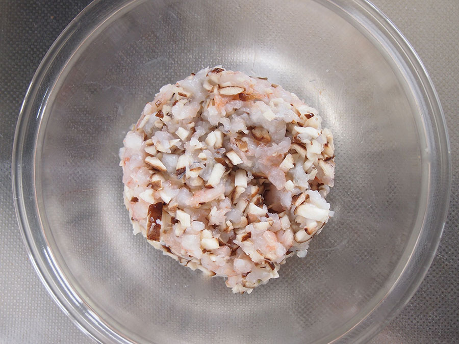 海老は包丁でミンチに。粘り気が出るまで刻んだら、ボウルに入れ、（1）の椎茸と混ぜ合わせる。