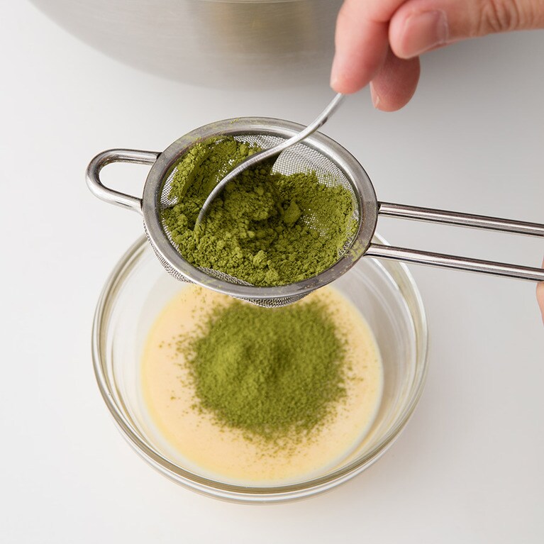 チーズ生地を大さじ3程度取り分け、抹茶パウダーを茶こしでふるい入れ、スプーンで混ぜて抹茶のチーズ生地を作る。