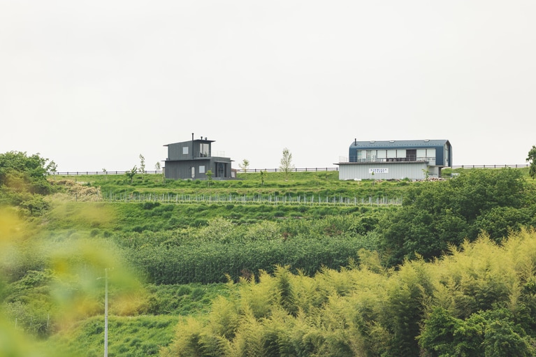 写真左の建物が、6月にオープンした「song」、写真右の建物が、丘の上にある「ジオヒルズワイナリー」の醸造所。（撮影：砺波周平）