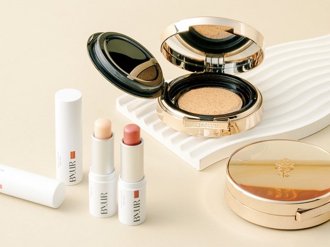 左：ハイライト・チーク・リップ・アイカラー・保湿ケアとマルチに使える話題のスティック。上品なツヤを叶えてくれる。バイユア セラムフィット ボリューミング グロースティック 全3色 2,090円／Hamee 
右：2008年に韓国で誕生したクッションファンデ。その後、2015年頃よりグローバルブランドが相次いでクッションファンデを発売。ランコムはその先駆けだった。アプソリュ タン クッションコンパクト 15,400円／ランコム