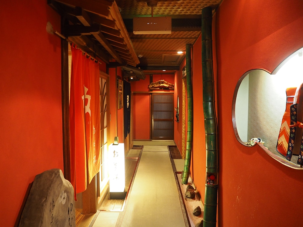 朱色の廊下がフォトジェニックな雰囲気。左側に大浴場の暖簾がかかる。