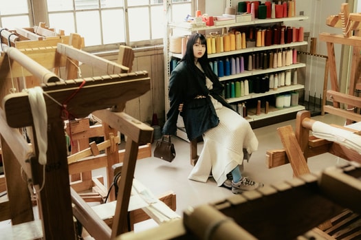 建物内では秩父銘仙の歴史や展示品を見ることができるほか、型染めや織りの体験も可能。木製の織り機や設備はすべて現役で使われているので、職人が織りを行う姿に出会えることも。菊池さん着用：ターギー フォー ウォータープルーフ ¥24,200／キーン（キーン・ジャパン）、ジャケット 96,800円、ベルト 36,300円／共にフミエタナカ（ドール）、ニットトップス 57,200円、ニットスカート 52,800円／共にオープン セサミ クラブ バッグ 37,400円／ルメメ、タイツ／スタイリスト私物