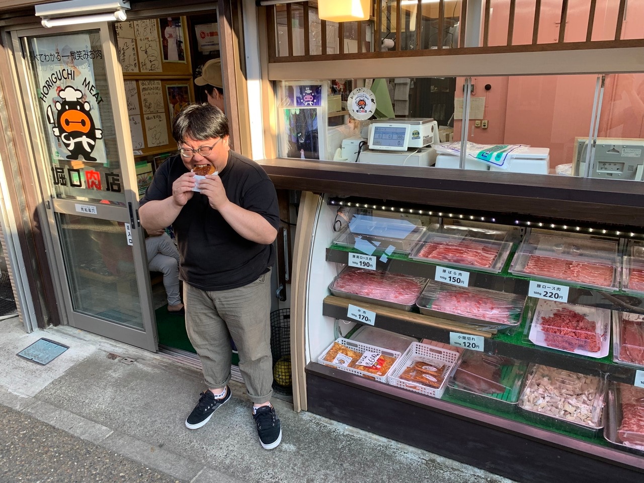 下仁田の「堀口肉店」で揚げ物にかぶりつく関さん。