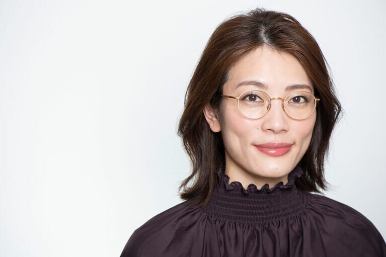 ツヤと彩りを効かせたメイクで、シンプルな眼鏡でも華やかな印象に。メタル素材の質感と品良く調和しています。