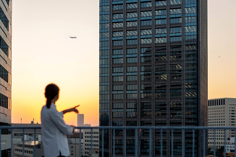 遠くの空に飛行機を見つけた長江さん。