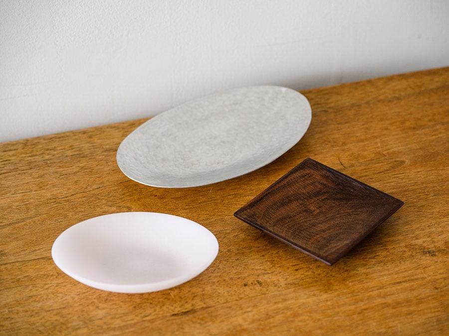 ガラスや木、アルミなど質感のまったく違う皿がひとつあると、見慣れた食卓の風景ががらりと変わる。