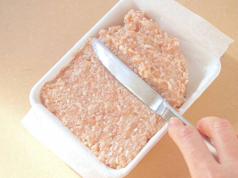 (4) バットなどのオーブン用容器にクッキングシートを敷き、(3)のタネを入れます。表面をナイフでならして平らにしましょう。