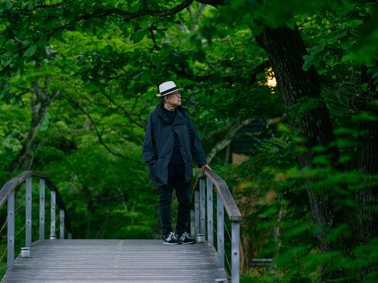 本来の植生を活かしつつ整えられた庭をのんびりと散策する松本さん。