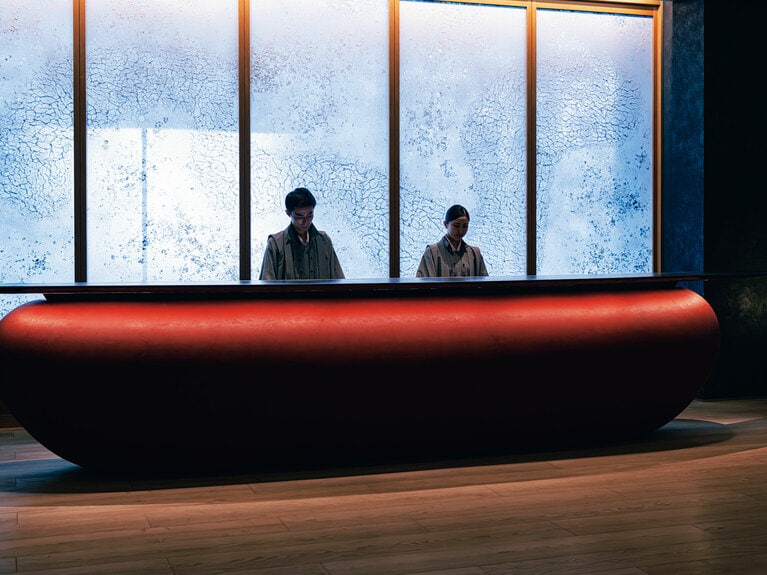 やわらかな曲線を描くレセプションは、伝統色の朱色のカウンターが印象的。