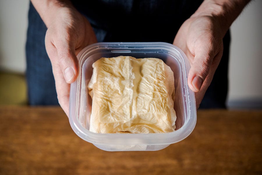 木綿豆腐は一度半分に切った上で、その断面を2枚重ねしたキッチンペーパーで包む感じにすると、効率よく水切りできます。