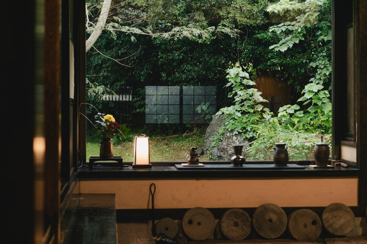 母屋に入るとすぐに広がる大きなガラス窓からの中庭の景色。陶芸家で花の木の主人でもある渡辺陶生さんの作品もいたるところに展示されています。