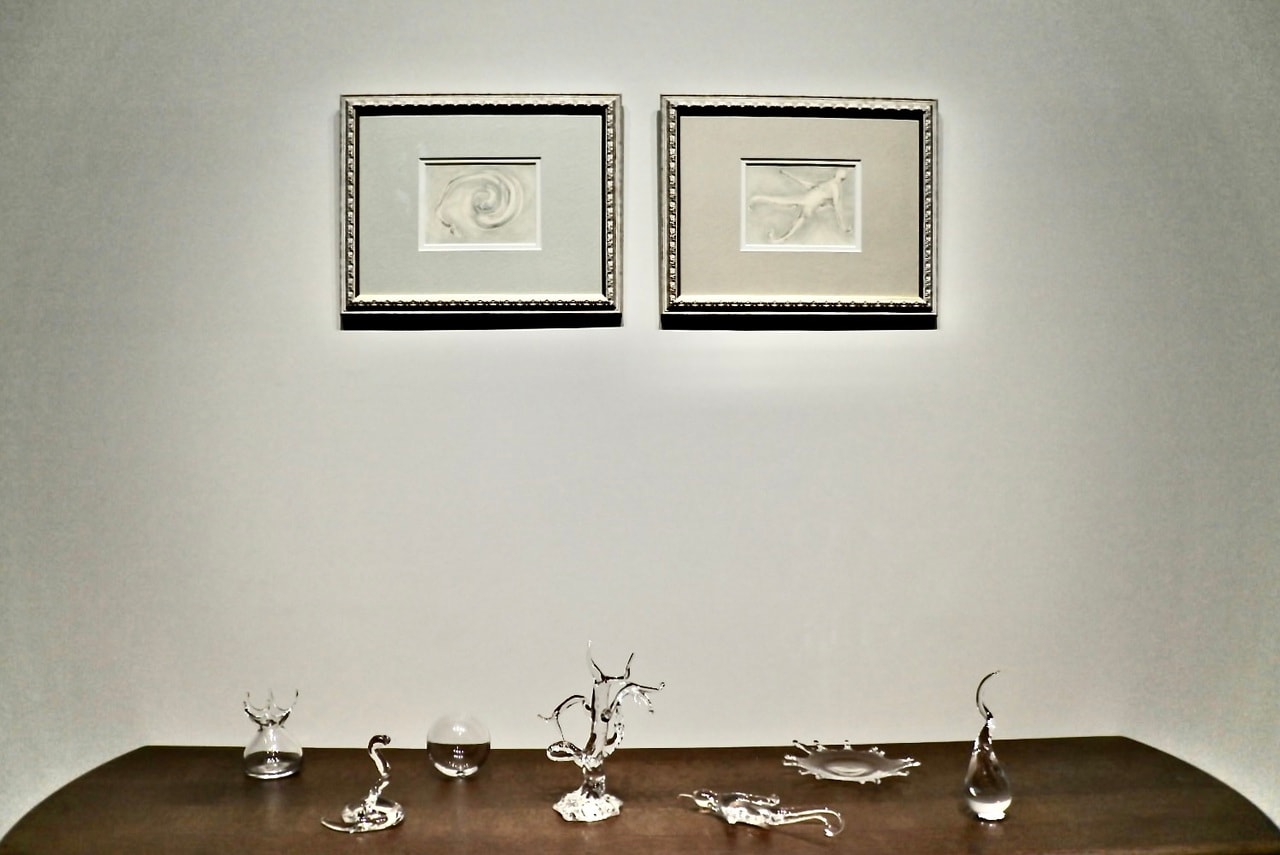 木々津鏡さんの展示。壁にはコピックや鉛筆で描いた《Glass Drawing》、テーブルにはガラスで制作した作品が並びます。