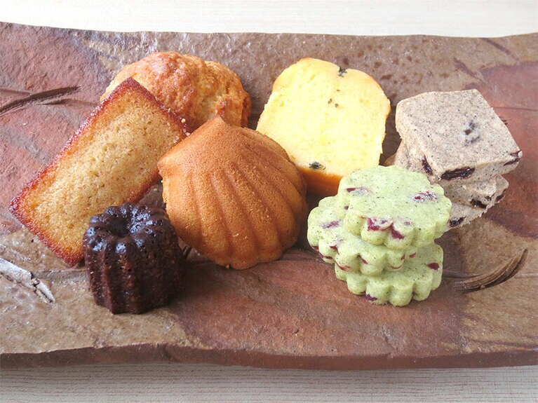 焼き菓子。左手前から時計回りで「お昼からのカヌレ」280円、「はちみつフィナンシェ」220円、「プレーンスコーン」250円、「小夏とぶしゅかんのパウンドケーキ」400円、「レーズンチャイのクッキー」1袋350円、「煎茶のショートブレッド」1袋350円、「マドレーヌ」250円(種類によって季節限定)。