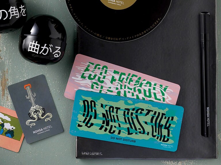 左から、日本唯一、手摺木版和装本を手がける「芸艸堂（うんそうどう）」とコラボしたカードキー〈K〉、注目のグラフィックデザイナー三重野龍氏によるドアサイン〈K〉、清水焼を代表する窯元のひとつ「嘉峰陶苑」のメモパッド〈K〉。