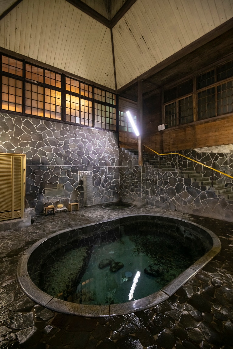 名物の立ち湯「白猿の湯」は深さ約1.25m。天然の岩を人力で掘った湯船も野趣に富む。
