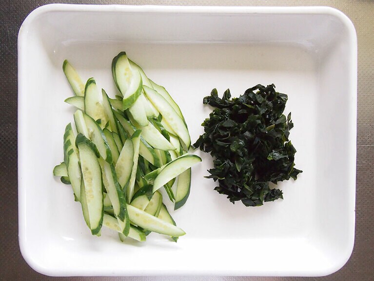 （2）（1）のわかめの水分を絞って、食べやすい大きさに切ります。きゅうりは縦半分に切り、斜めの薄切りにします。