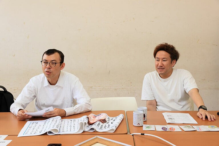 サイン会にちなんで発売されるオリジナルグッズと2人。グッズを3,300円以上購入するとノベルティステッカーが1枚もらえます。