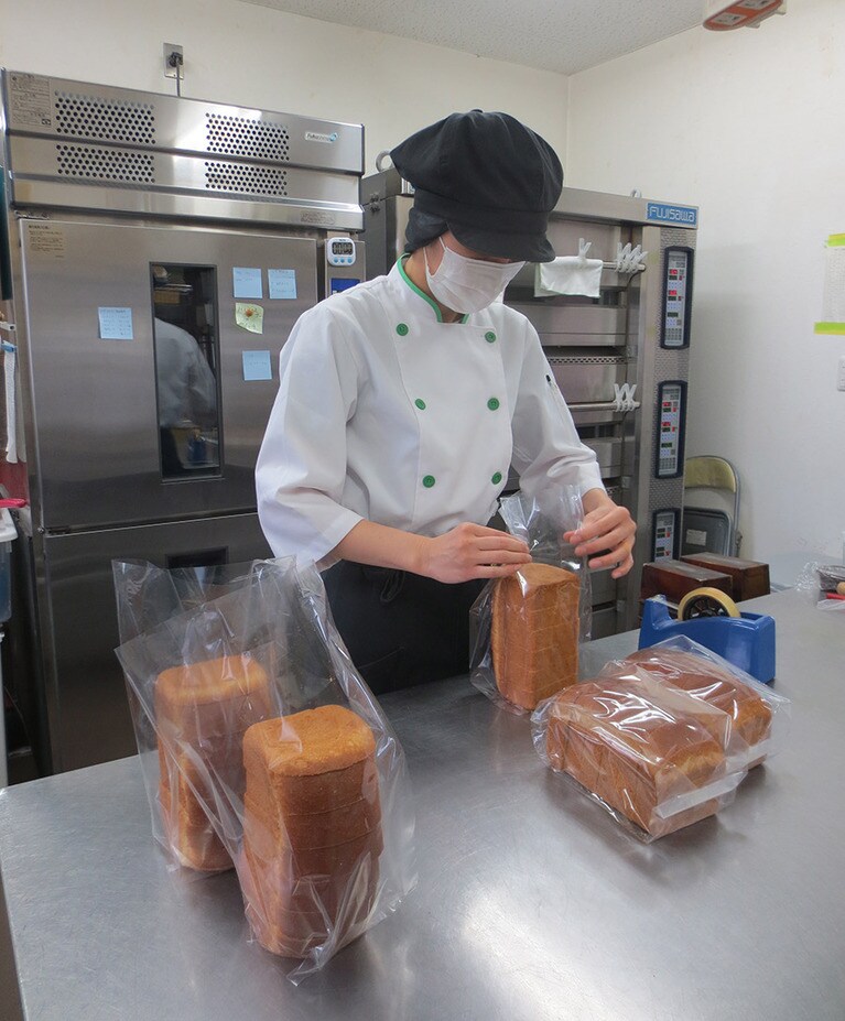駅舎を使った工房でスタッフが丁寧にパンの袋詰め作業中。