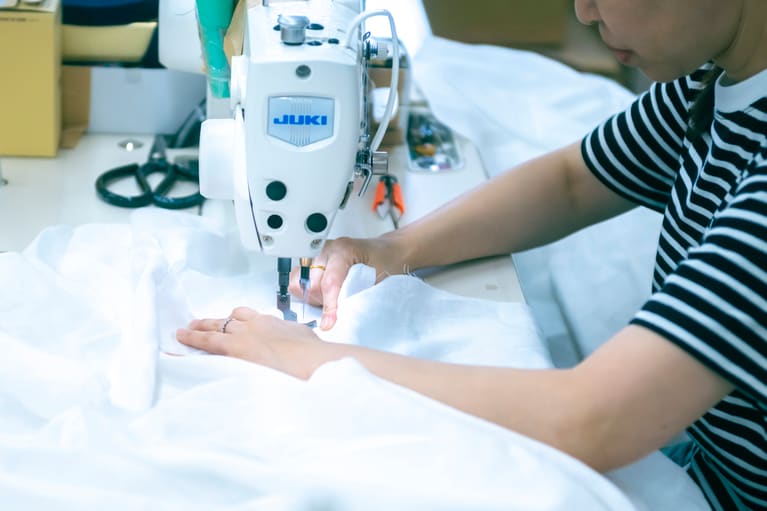 縫製においては、大まかに衣服を形づくる工程と、ボタンホールや襟、フリルなどの細部を作る工程があり、それぞれのパーツの縫製の技術に長けた職人が担当します。