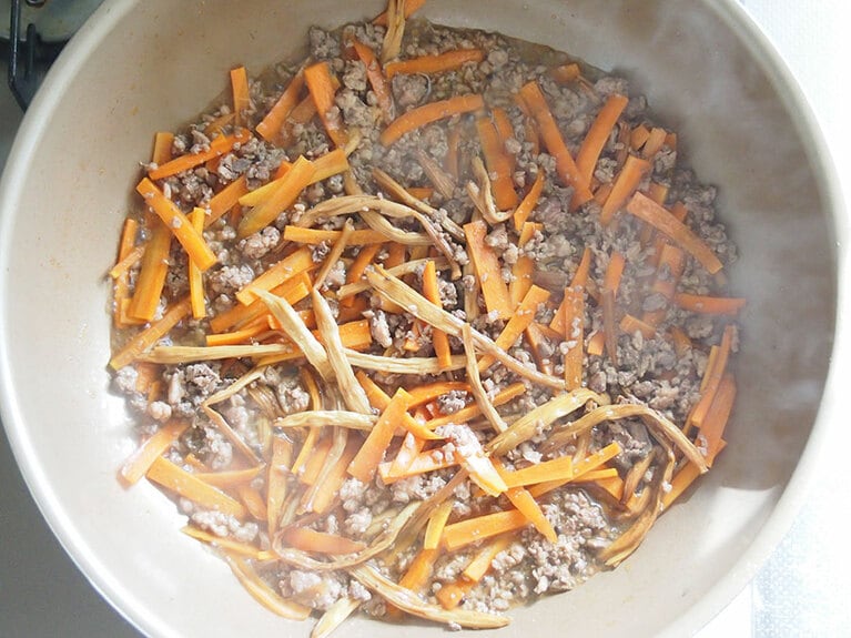 金針菜は、戻し汁とともに入れ、人参、仕上げ調味料を入れて沸騰させながら中火で炒める。