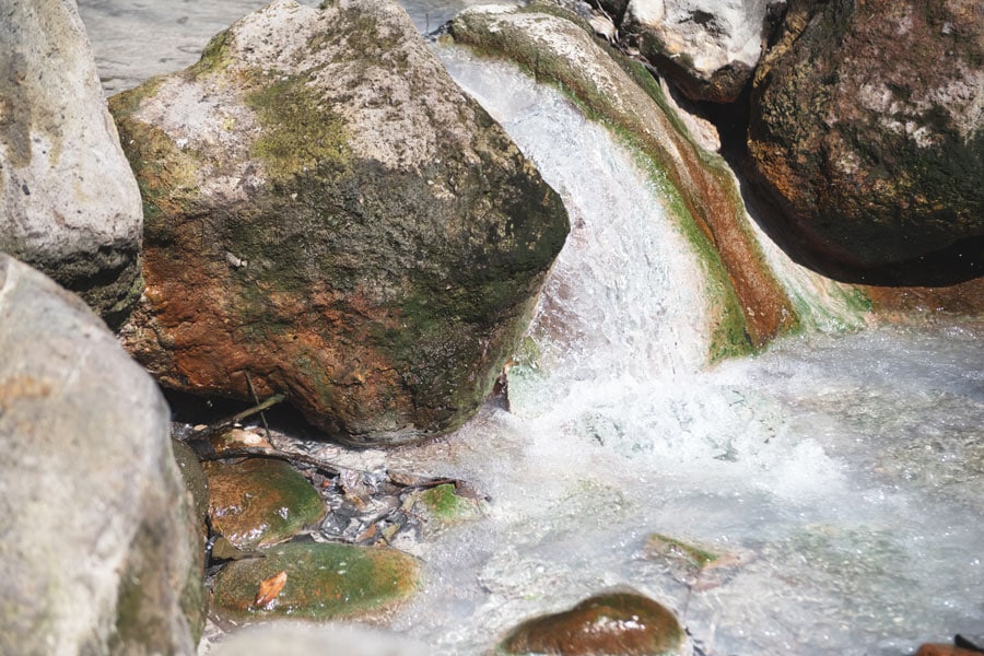 公園内の清流のすぐ近くにも温泉が湧き出て流れている。岩が温泉の強い成分で変色しているのがわかる。
