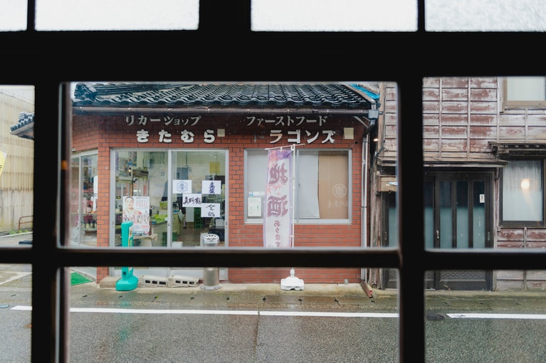 NIPPONIA 佐渡相川金山町の目の前にある、「リカーショップきたむら」。チェックインのときにもらったドリンクチケットを持っていき、「これに合うおつまみって、どんなのがありますか？」なんて会話も。そんな何気ないひとときに、旅人と町との新しいつながりが生まれていきます。