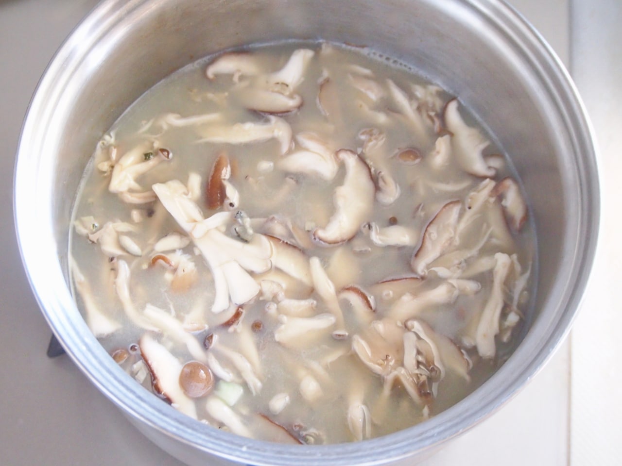 キノコがしんなりしてきたらヒタヒタになるくらいの量の水を入れて煮込む。