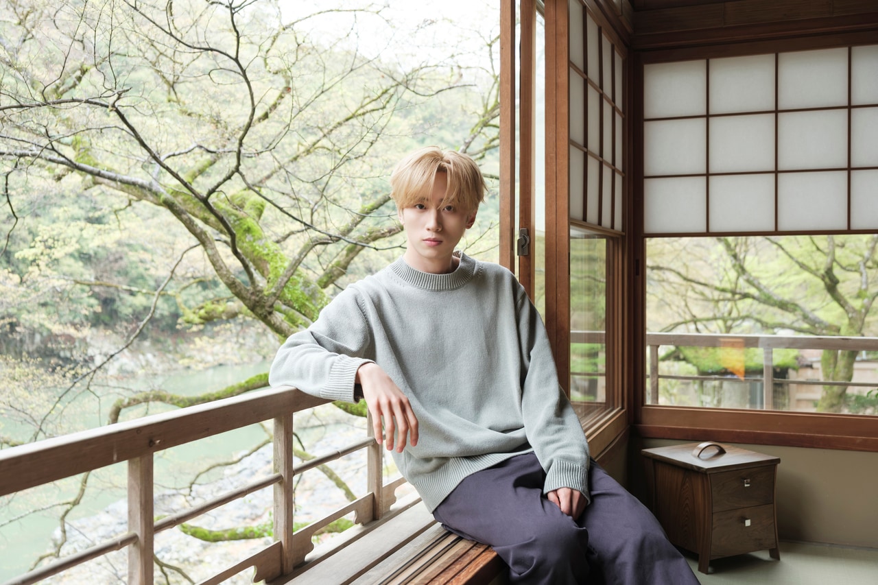 大堰川と対岸の小倉山を望む客室でくつろぐ豊凡さん。ニット 25,300円／MHL.、パンツ 34,100円／Y（イレーヴ）