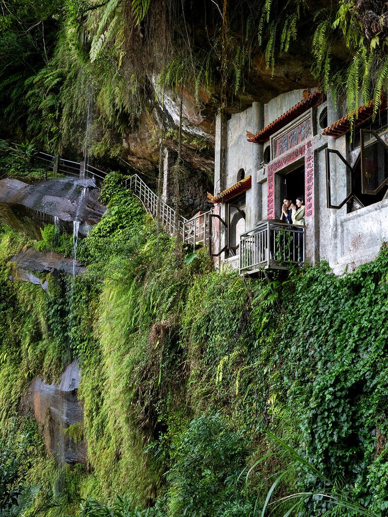 歩道から見上げた銀河洞。左にご神体の滝が。手を合わせる人の姿も。MRT松山新店線・新店駅からバスで「銀河洞」下車、さらにコース入り口まで徒歩30分ほど。入り口までタクシーで行くこともできる。