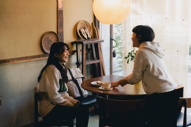 原さん（右）の笑顔とおいしいスイーツが歓待してくれる。ジャケット ミラクル ミッドレイヤー ジャケット アジアンフィット 25,520円、パンツ マウンテン タフ パンツ アジアンフィット 16,500円、リュック エクセロン15 14,300円、シューズ サーティグ 2 ミッド ゴアテックス 27,500円／すべてマムート