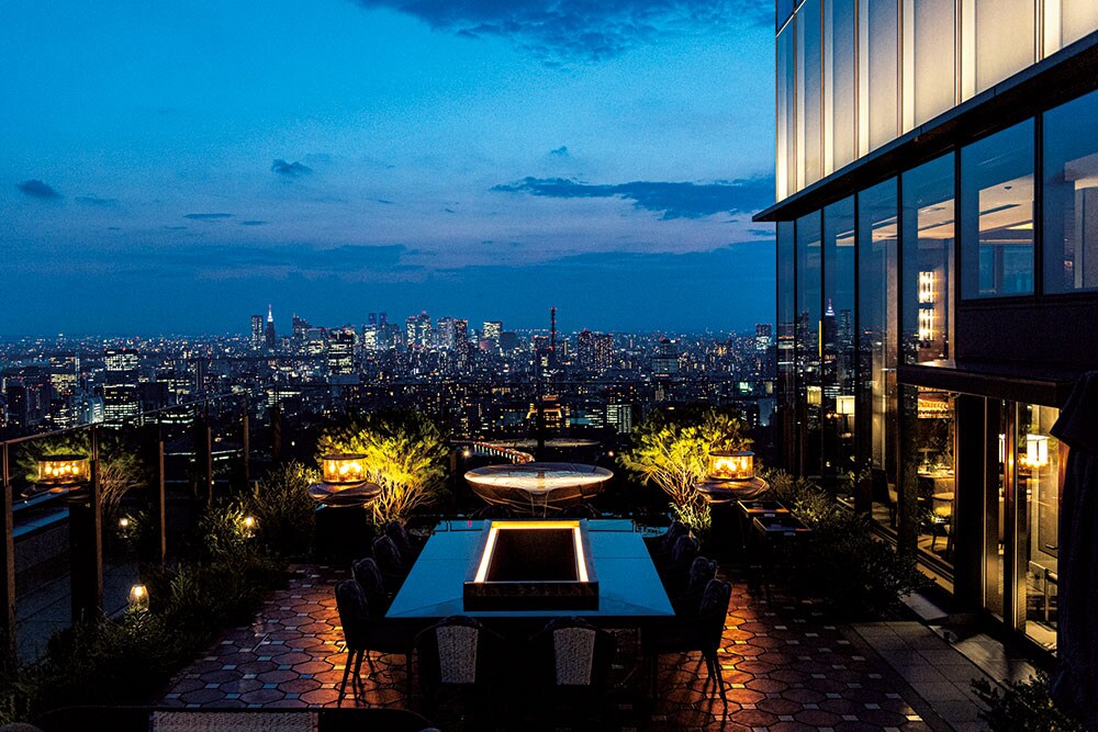 天空ガーデンとファウンテンの向こうに壮大な東京の夜景が広がるイタリアンダイニング「ピニェート」のアウトドアテラス。