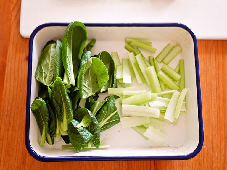 小松菜の茎は4センチ長さに、葉は2等分に切る。