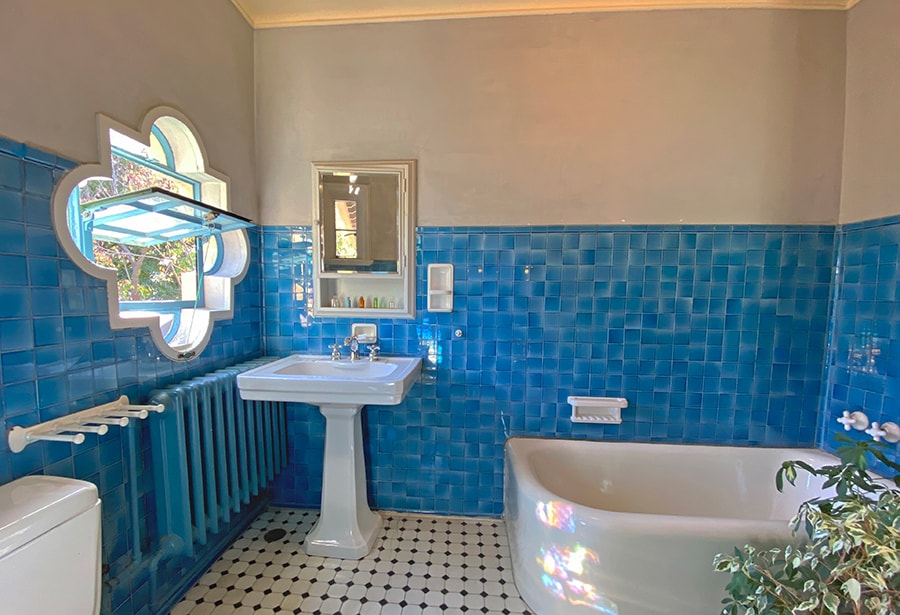 青いタイルが美しいゲストルームの浴室。時間帯によっては、小窓の反射がステンドグラスの光のようにも。