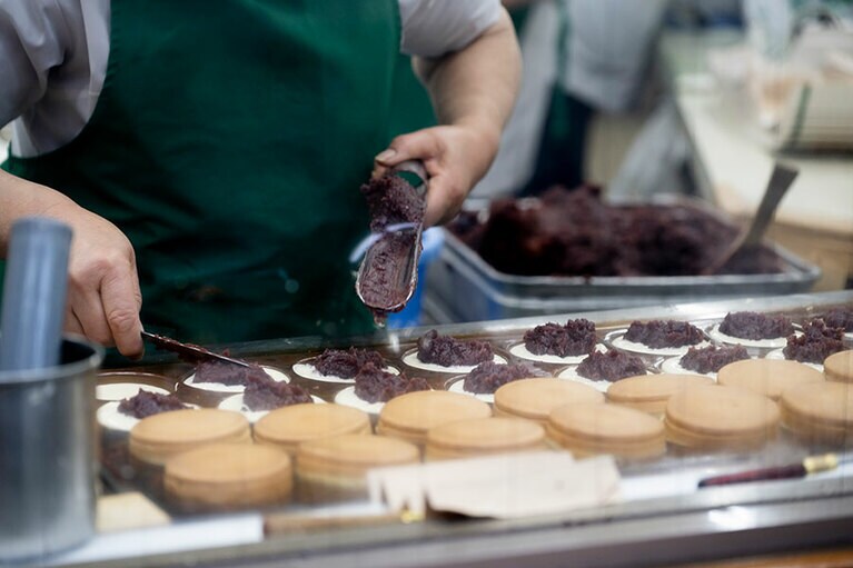 作っている様子がガラス越しに見える、熊本のソウルフード「蜂楽饅頭」。蜂蜜が練り込まれた生地の中に黒餡もしくは白餡が入っており、OMOレンジャーはマチに行ったら必ず買うそう。平日の昼にもかかわらず、購入客の列ができていました。