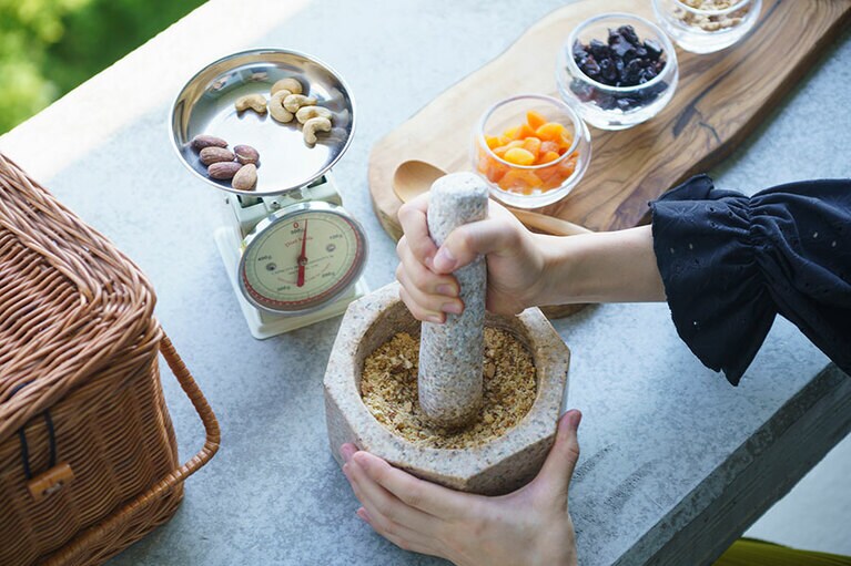 ナッツやドライフルーツを石臼でたたき、ココナッツオイルでまとめる。