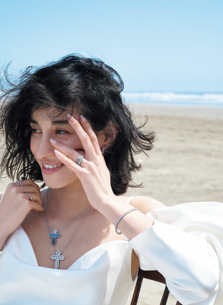 薬指に光るのは、繊細なデザインで魅了するリング、胸元には聖なるクロス。アイコニックな「ベル エポック」をまとえば、まさに古き良き時代＝ベルエポックを生きた女性たちのように、たおやかな美しさを増して。 
〈左手・薬指先上から〉「ベル エポック」エタニティリング （PT×DIA）492,800円、エンゲージリング（PT×センターDIA0.3ct～）723,800円～、エタニティリング（PT×DIA）1,122,000円 〈右手・人差し指〉エタニティリング（PT×DIA）781,000円 〈右手・薬指〉リング（PT）278,300円 ピアス（WG×DIA）899,800円 「ベル エポック ・クラウン アイスバーグ」ネックレス〈上〉（WG×DIA×サファイア＊100周年限定）1,364,000円、〈下〉「ベル エポック・クラウン」ネックレス（WG×DIA)1,925,000円 「ルーチェ」ブレスレット（WG×DIA）1,441,000円／すべてダミアーニ（ダミアーニ 銀座タワー） ドレス539,000円（レンタル価格）／マルケーザ（ミラー ミラー 丸の内）