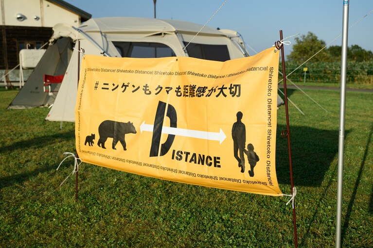 「＃ニンゲンもクマも距離感が大切」と書かれたバナー。知床ではヒグマと最低限とるべき距離を50mと定めている。