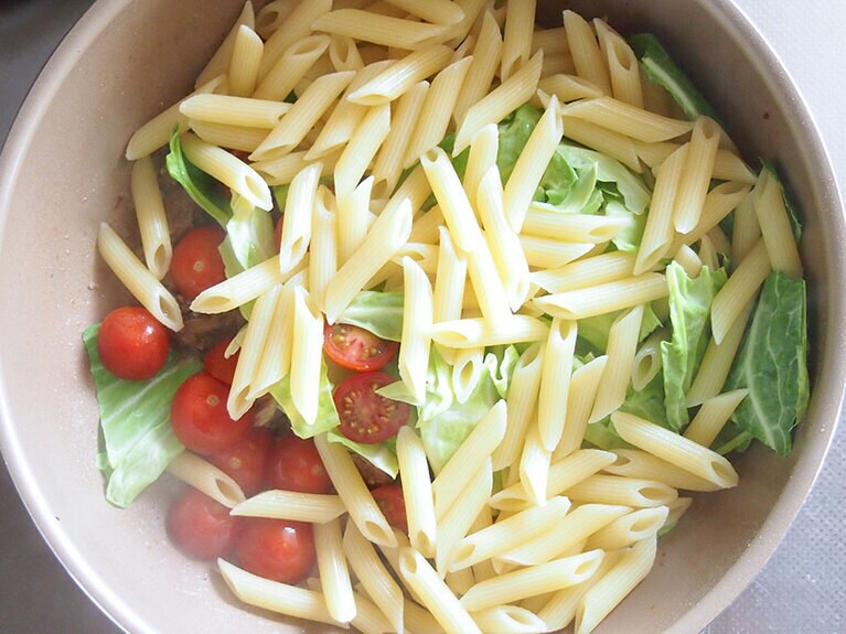 (4) 別鍋に湯を沸かし、パスタを茹でます。(3)のフライパンに茹で上がったパスタ、キャベツ、ミニトマトを入れて加熱します。