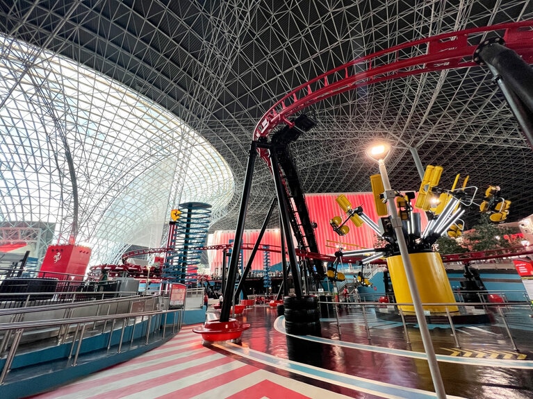 黄色い椅子が宙に浮いてぐるぐる回る「フライング・ウィング」。その上の赤いレールは、子供用屋内コースター「フォーミュラ・ロッサ・ジュニア」のレールだ。