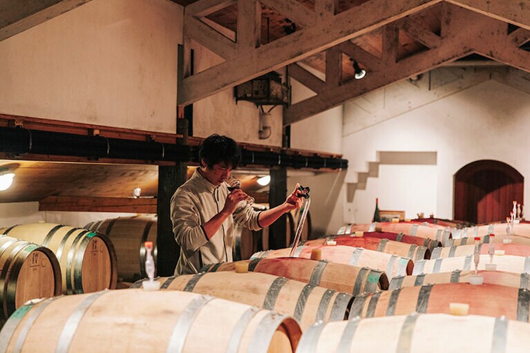 【Winerystay TRAVIGNE】熟成庫で仕上がりを見る醸造家の掛川史人さん。Photo: Masahiro Shimazaki