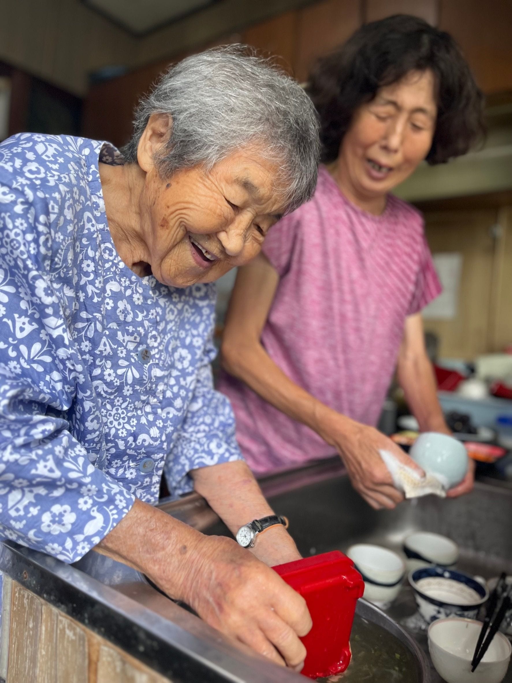 台所に立つ哲代さんとよりちゃん（近所の兼久世利子さん、 70歳）。手を動かしながら、気の合う二人のおしゃべりは止まらない
