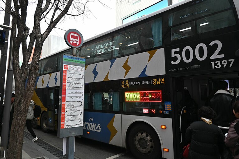 エバーランドと駐車場の間を運行するバス（写真左）。江南のバス乗り場（写真右）。5002のバスがエバーランドを通る。2024年2月29日（木）撮影。