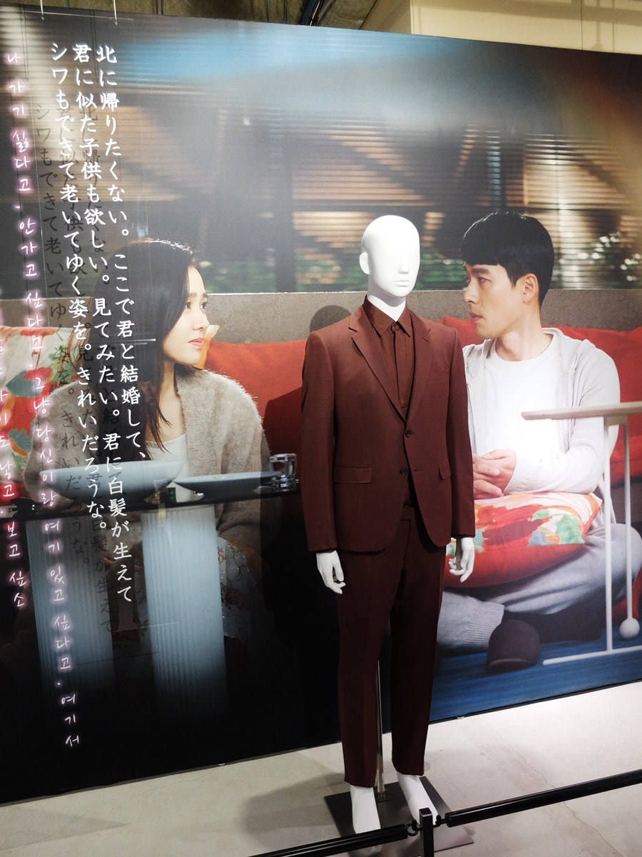 韓国のシーンで、茶色のスリーピースを颯爽と着こなしたリ・ジョンヒョク。