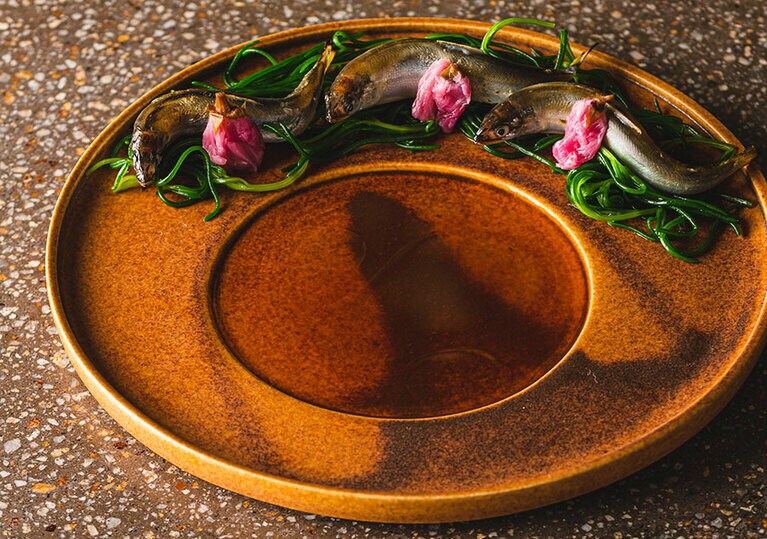 コースの一品。鮎の塩焼きを桜のピクルスと。