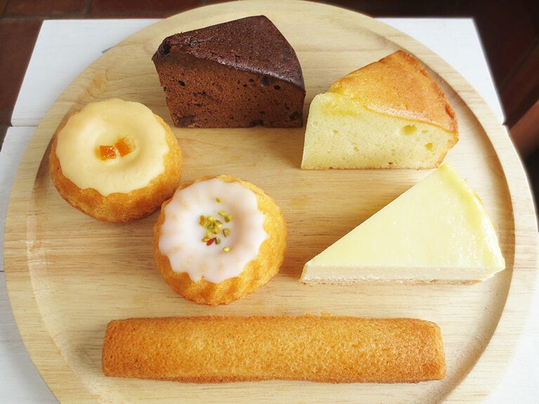 右上から時計まわりに：「チーズケーキ」280円、「バニラビーンズが香るしっとりケーキ」210円、「フィナンシェ」160円、「レモンのケーキ」200円、「パッションフルーツのケーキ」200円、「コーヒーとチョコの大人ケーキ」210円。