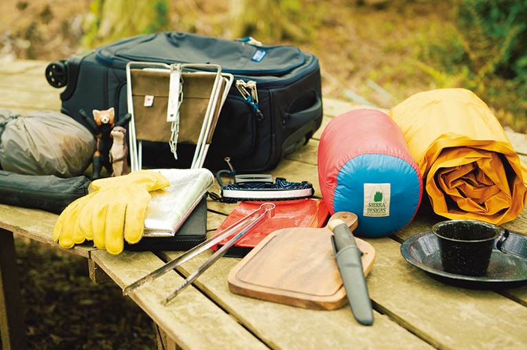 右から時計回りに：「サーマレスト」のマットレス、ホーローのカップ&皿、「シエラデザインズ」の寝袋、「モーラナイフ」のナイフ、カッティングボード、「ハーキンス」のヘッドライト、「モンターニュ」のミニテーブル、トング、「ベストメイド」の椅子、「ベルモント」の焚き火プロテクトシート、ウルフ&グリズリーの焚き火台、革手袋、「ムラコ」のテント／すべて猪野さん私物