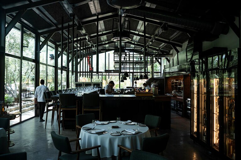 メインホールにはオープンキッチンのシェフズテーブルが25席、60のテーブル席のほかにテラス席もある。