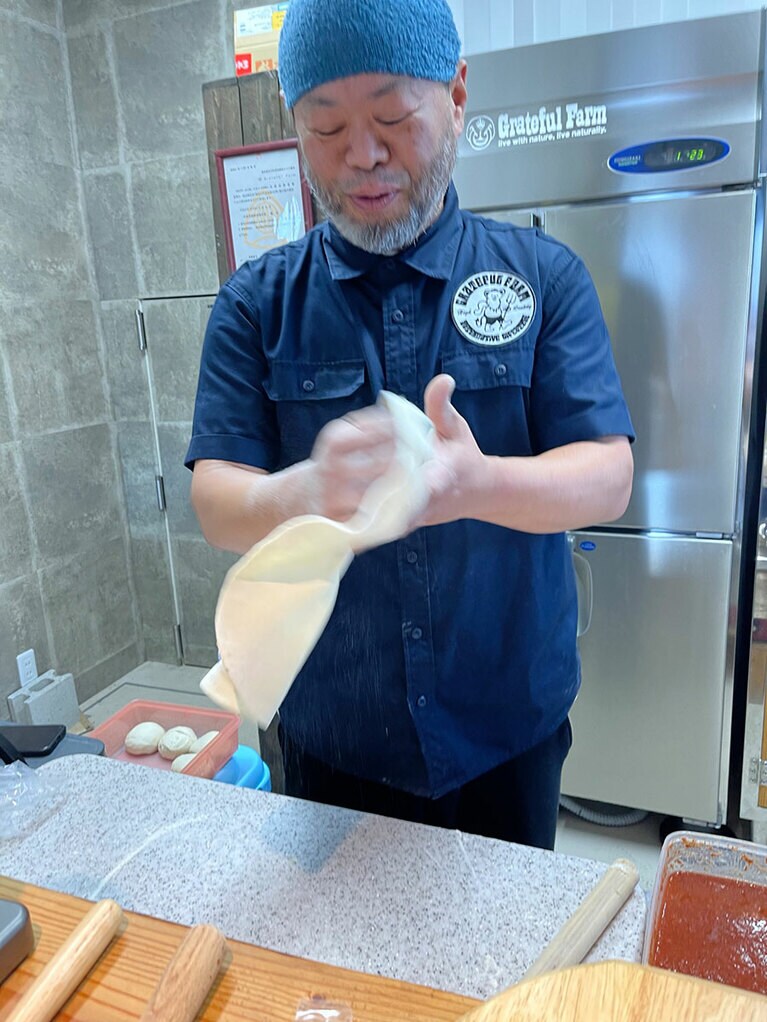 ピザ生地を伸ばす松岡さん。